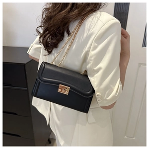 Détail d'un sac à bandoulière en cuir mat noir avec chaîne dorée et coutures ondulées