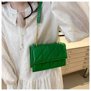Detail of green quilted crossbody bag with gold chain strap on female model