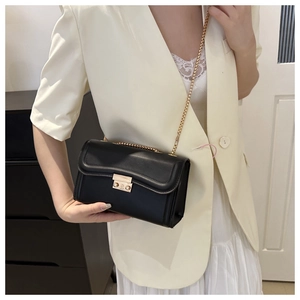 Gros plan du sac en cuir noir avec chaîne dorée et boucle métallique rectangulaire chic