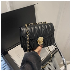 Détail d'un sac bandoulière noir matelassé avec chaîne dorée et fermoir rotatif