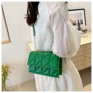 Green quilted leather crossbody bag with gold chain strap shown on white dress
