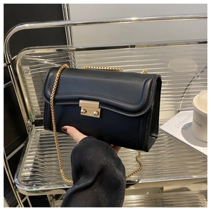 Détail du sac bandoulière en cuir noir avec chaîne dorée et fermoir en métal poli