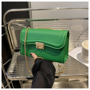 Détail du sac en cuir vert émeraude avec bandoulière en chaîne dorée et boucle carrée