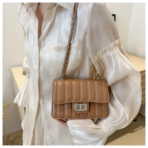 Detail of caramel quilted bag with diamond turn-lock and woven chain strap on model