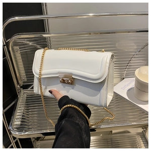 Détail du sac blanc avec chaîne en métal doré et fermoir au design urbain élégant