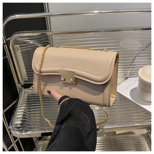 Détail du sac à bandoulière beige avec rabat ondulé et chaîne dorée sur support