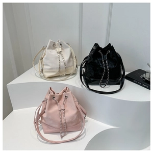 Three drawstring bucket bags in beige, black, and pink with silver chain accents