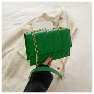 Detail of green quilted crossbody bag showing chain strap and geometric texture