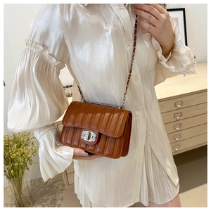 Sac bandoulière matelassé marron avec fermoir en cristal porté par un mannequin chic