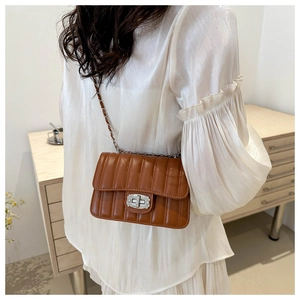 Detail of brown quilted chain bag with silver metallic twist lock closure for women