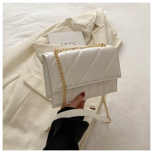 Detailed close-up of a white quilted crossbody bag with golden chain and faux leather strap
