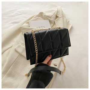 Detailed macro view of black quilted leather texture and golden metal chain on crossbody bag