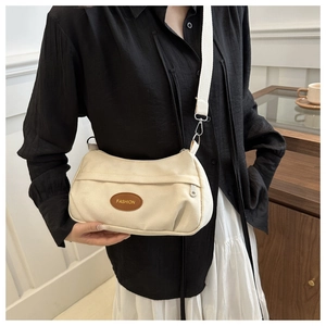 Detail of beige canvas crossbody bag featuring a fashion patch and adjustable strap