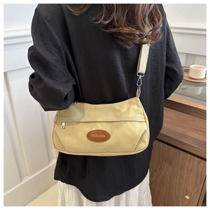 Macro detail of beige canvas crossbody bag with Fashion logo patch and wide strap