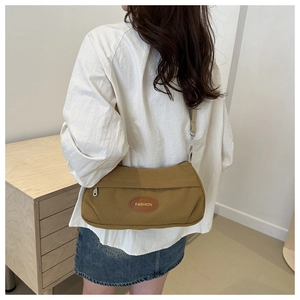 Detail view of khaki canvas shoulder bag with fashion leather patch and silver buckles