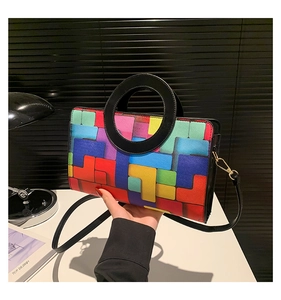 Détail d'un sac à main patchwork géométrique coloré avec anse ronde noire et garniture dorée