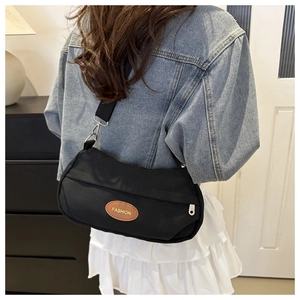 Detailed back view of a black canvas crossbody bag with fashion leather patch on denim