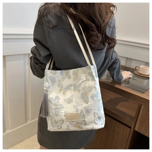 Détail de la broderie papillon élégante et du pompon sur un grand sac cabas