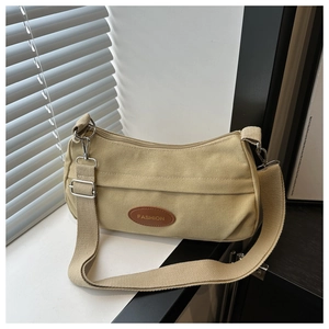 Close-up of canvas crossbody bag with tan leather fashion patch and metal buckles