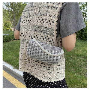 Detail of silver mesh bag featuring elegant white pearl handle and metallic texture