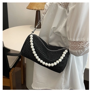 Close-up of black rhinestone pillow bag featuring pearl handle and silver chain strap