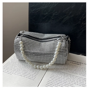 Macro shot of silver rhinestone cylinder bag with pearl handle and metal zipper detail