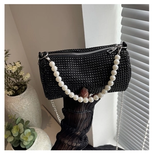 Detail of elegant black rhinestone purse featuring pearl handle and silver chain