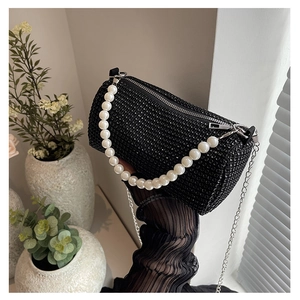 Close-up of black rhinestone cylinder bag with pearl handle and silver chain strap