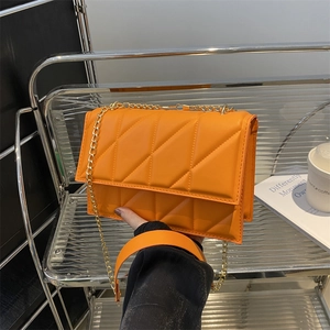Quilted orange chain crossbody bag with gold hardware and flap closure in luxury style