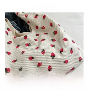 Gros plan du sac cabas en velours côtelé blanc avec motif fraise et tissu texturé