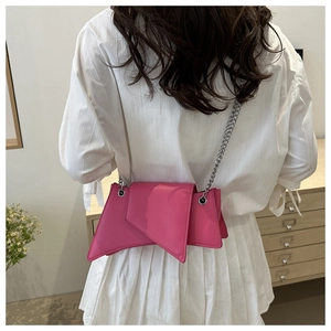 Detail of pink asymmetric geometric chain bag worn over the shoulder by a model