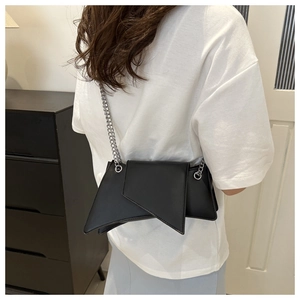Model wearing a black asymmetric geometric chain bag with silver shoulder strap