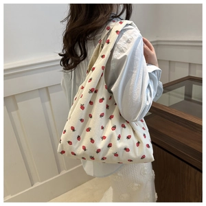 Texture détaillée d'un sac cabas en velours côtelé blanc avec imprimé fraise sur modèle