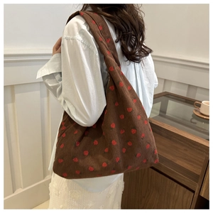 Détail d'un sac fourre-tout en velours côtelé marron avec des imprimés fraises rouges