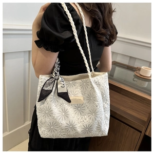 Detail of white quilted tote bag with daisy embroidery and decorative ribbon scarf