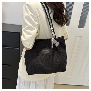 Detail of black pleated tote bag with woven shoulder strap and decorative silk scarf