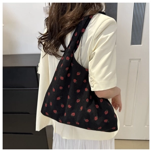 Gros plan d'un sac cabas en velours côtelé noir avec broderie de fraises délicates