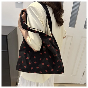 Détail de la broderie fraise sur un sac cabas en velours côtelé noir avec texture