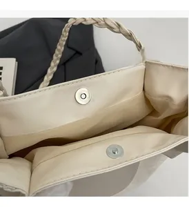 Détail des boucles magnétiques argentées et de l'anse tressée du sac cabas beige