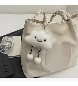 Détail d'un sac cabas en simili cuir beige avec poignées tressées et charme nuage