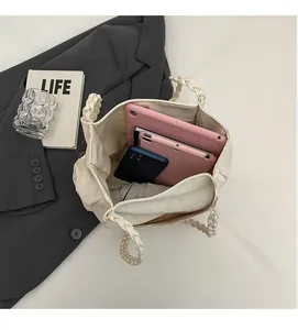 Vue de dessus d'un grand sac fourre-tout crème avec anse tressée et objets du quotidien