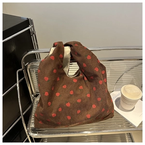 Détail d'un grand sac cabas en velours côtelé marron avec motifs fraises rouges