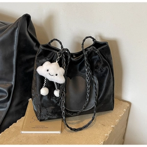 Détail d'un cabas en velours noir avec patch cœur et breloque nuage sur socle en pierre