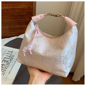 Detailed close-up of pink jacquard handbag with traditional embroidery and metal lock