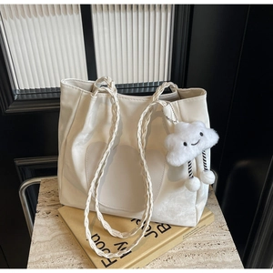 Gros plan détaillé d'un sac cabas en cuir blanc avec patch cœur et breloque nuage en peluche