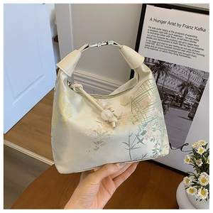 Detail of cream Chinese-style handbag with floral embroidery and beaded drawstring charm