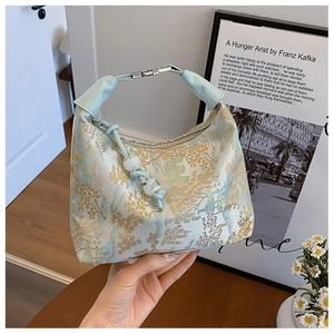 Detailed close-up of intricate Chinese embroidery on a light blue silk handbag