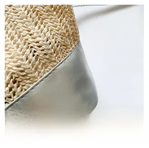 Détail du sac seau en paille tressée avec empiècements en cuir argenté métallisé aux coins