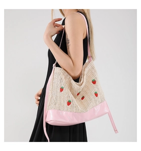 Détail du sac seau tressé avec broderie de fraises et finitions en cuir PU rose