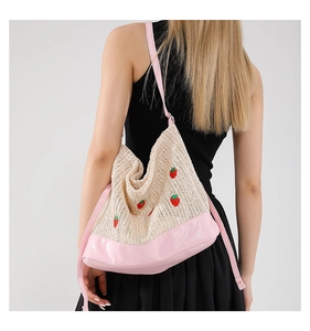 Détail du sac seau tissé avec broderie fraise et bandoulières en cuir rose